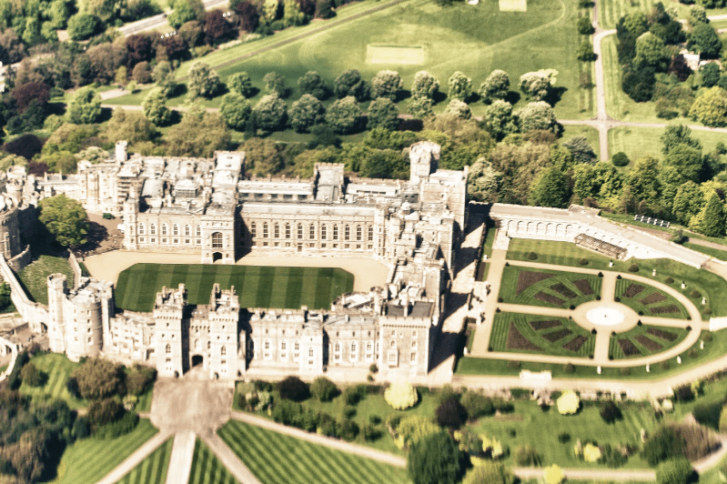 Tourist Attractions in England, Aerial view of a historic castle featuring extensive gardens and landscaped grounds.